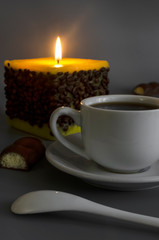 Cup of coffee on a background of a burning candle