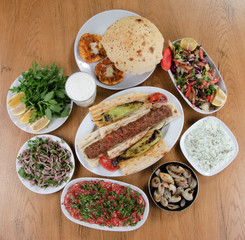 Traditional Turkish Adana kebab or kebap meat food, appetizers, ayran and salgam on table from top view in turkish restaurant.