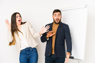 Young caucasian business couple isolated being shocked due to an imminent danger