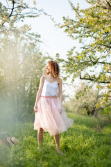 Young attractive girl walks in spring green park enjoying flowering nature