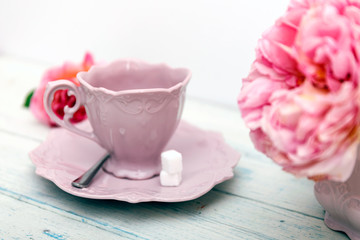 Pink peonies in vase and cup of tea