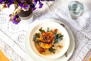 Fish soup with fish, wakame seaweed and onion circles on lacy placemat.