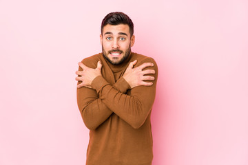 Obraz premium Young caucasian man against a pink background isolated going cold due to low temperature or a sickness.