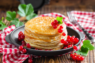 Thin french crepes stacked with fresh berries on wooden rustic table, closeup
