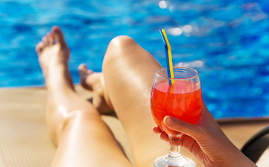 Woman with cocktail lying near the swimming pool.