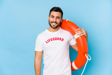 Young handsome lifeguard man isoalted happy, smiling and cheerful. - obrazy, fototapety, plakaty