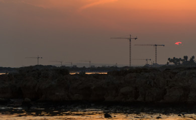 Lots of construction cranes near Ayia Napa in Cyprus on sunset.