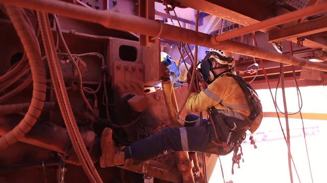 Footage of male rope access welder wearing safety equipment, glove protection working on twin rope abseiling performing welding maintenance structures metal repairs on construction site, Perth, OZ