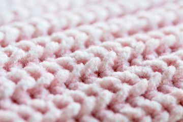 Macro of pink knitted wool pattern, soft focus. Close-up of a fragment of knitted warm sweater. Thick pink wool yarn. Diagonal arrangement