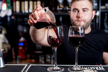 Bartender pours red wine into a glass. Sommelier. Restaurant. Nightlife
