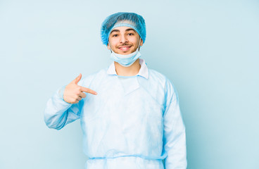 Young arabian surgeon man isolated against on a blue background person pointing by hand to a shirt copy space, proud and confident