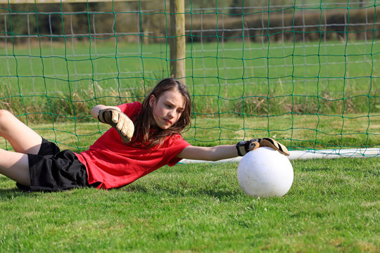 Young Girl Goalkeeper Saving A Football.
