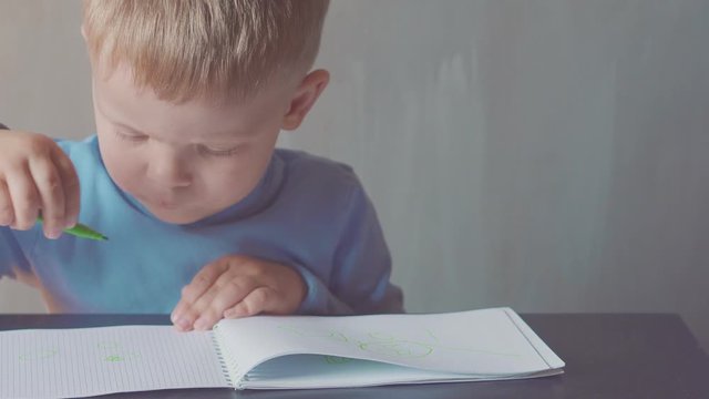 two year old boy is drawing with marker at album