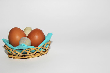 chicken and quail eggs in a basket on a white background