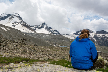 Female mountaineer resting on a rock surrounded by spectacular mountain views.