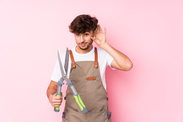 Young arab gardener man isolated trying to listening a gossip.