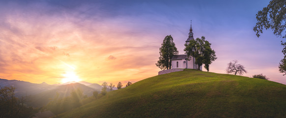 Astonishing colorful summer sunset in Slovenian Alp mountains with St Tomaz church. Travel destination Slovenia