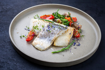 Italienisches Gourmet Kabeljau Fisch Filet mit Brokkoli, Meeresspargel und Tomaten als closeup auf einem Modern Design Teller