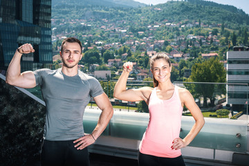 Two young adult fitness models posing on rooftop.