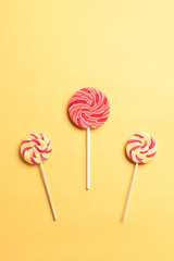 colorful swirl lollipops on a yellow background. National Candy Day. vertical image