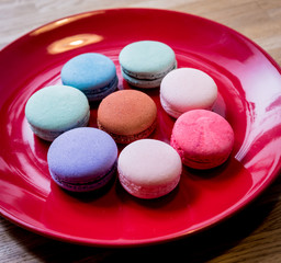 French colorful macarons on a red plate. Restaurant.