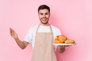 Young caucasian baker man isolated receiving a pleasant surprise, excited and raising hands.