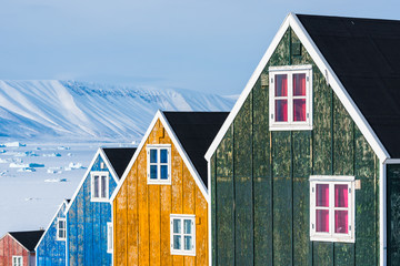 Row of colourful wooden houses against a landscape of snow drifts