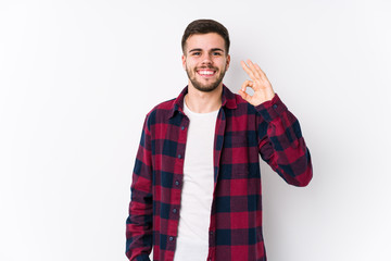 Young caucasian man posing in a white background isolated cheerful and confident showing ok gesture.