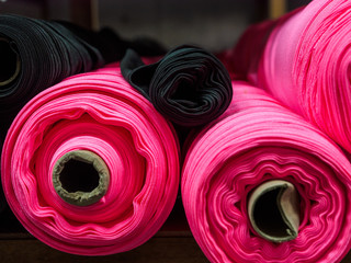 Pink and other rolls of knitted fabric. Woven warehouse
