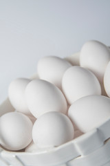 White eggs in a ceramic white corp on white background