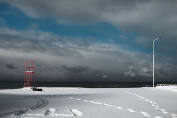 Red lifeguard tower on the snow covered beach