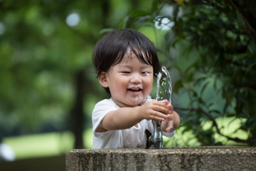 公園で水遊びをする無邪気で元気な男の子.