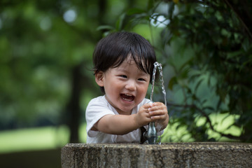 公園で水遊びをする無邪気で元気な男の子.