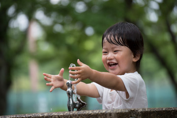 公園で水遊びをする無邪気で元気な男の子.