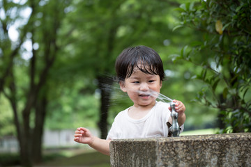 公園で水遊びをする無邪気で元気な男の子.