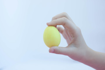 Hand holding a yellow egg painted for the Easter holiday selective focus