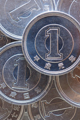 Japanese coins at 1 yen close-up. The surface of many of these coins. Information and news about the economy, finance, banks of Japan. Vertical shot. Macro