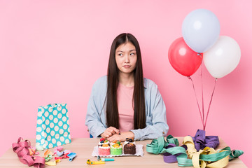Young chinese woman organizing a birthday isolated confused, feels doubtful and unsure.