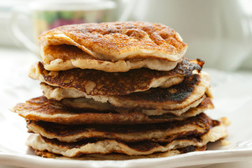 Low Carb Keto Diet Pancakes from almond coconut flour stack on white plate background close up view. Selective focus. Copy space. Ketogenic concept