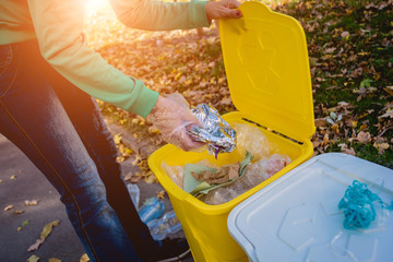 Volunteer girl sorts garbage in the street of the park. Concept of recycling. 