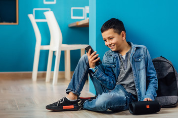 A boy in the room with a phone in his hands connects a music column on bluetooth.