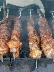 Cooking barbecue on coals. Pieces of rosy meat strung on metal skewers. Harmful and hazardous food containing carcinogens.