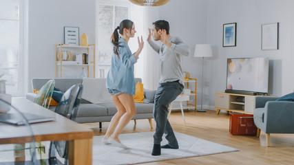 Happy Beautiful Couple is Having Fun and Actively Dancing in their Cozy Living Room at Home. They Smile and Laugh.