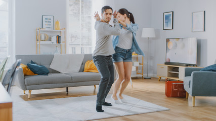 Happy Beautiful Couple is Having Fun and Actively Dancing in their Cozy Living Room at Home. They Smile and Laugh.