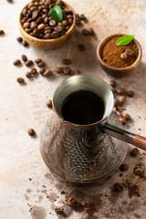 Morning coffee concept. Turkish coffee in Turk and coffee beans on a stone or slate countertop.