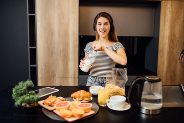 Young woman making breakfast with granola and milk , fresh food on table in the modern kitchen at home.