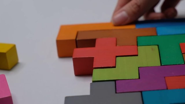 Closeup Slow motion. Hand holding piece of wooden block puzzle. wood cube stacking. Concept of complex and smart logical thinking.