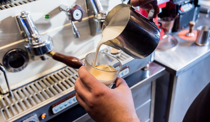 The bartender makes the coffee, cappuccino, cocoa, drink at the bar. 