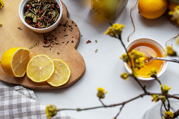 Dried green tea leaves on wooden board with lemon slices and honey. Tea composition concept. Spring branch