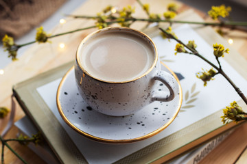 Cup of coffee and a book on a wooden background with yellow flowers. Workplace. Cozy breakfast. Spring concept